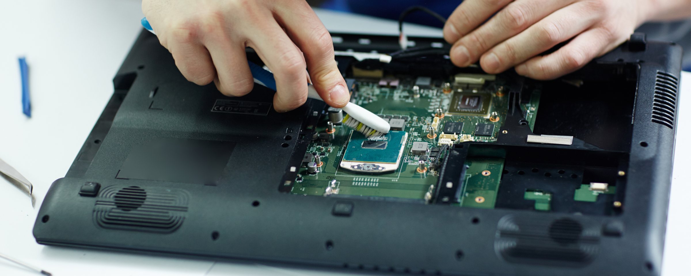 Técnico limpando a placa de um notebook durante a revisão